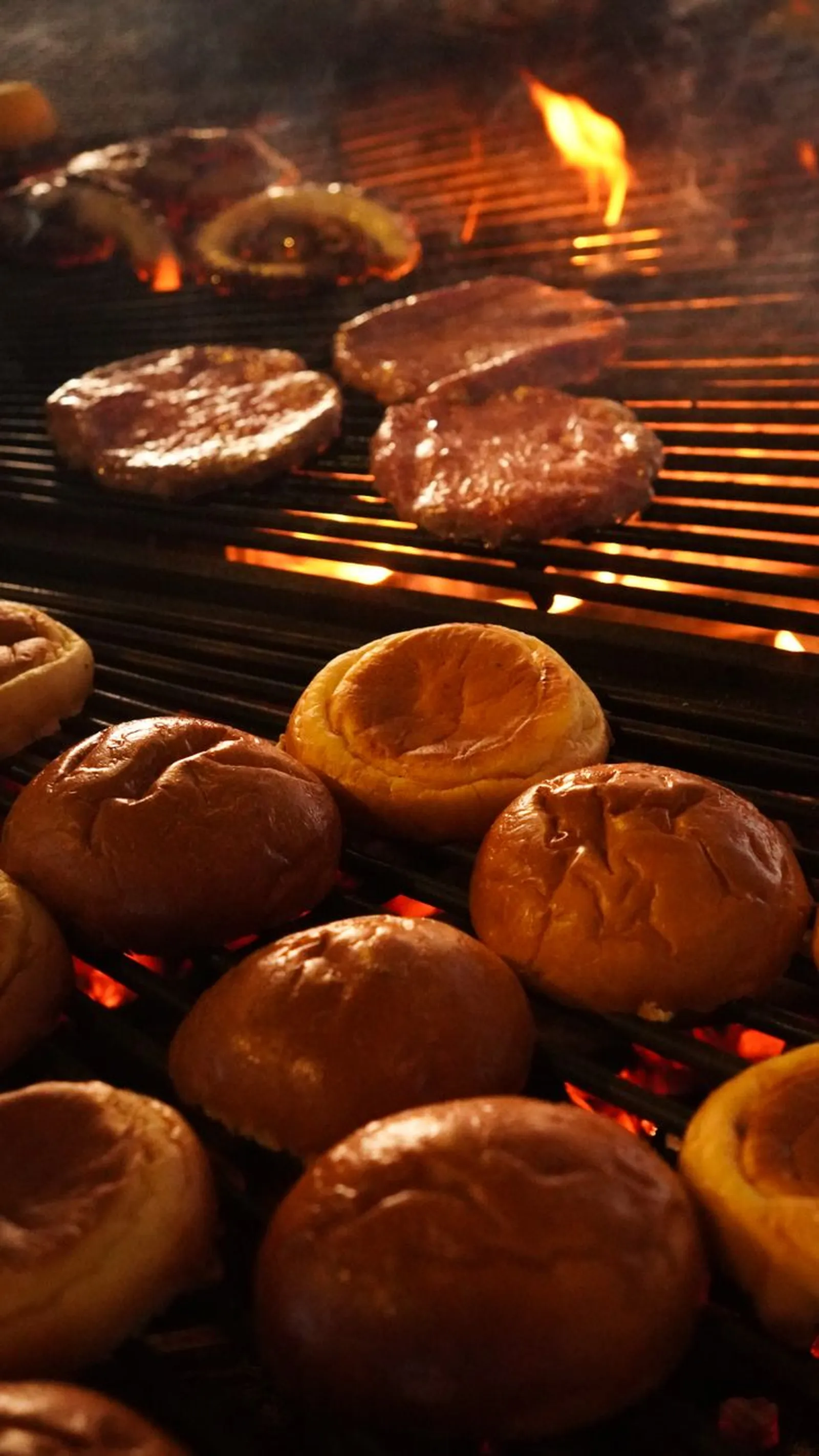 Burger-Patties über offener Flamme (Symbolbild)